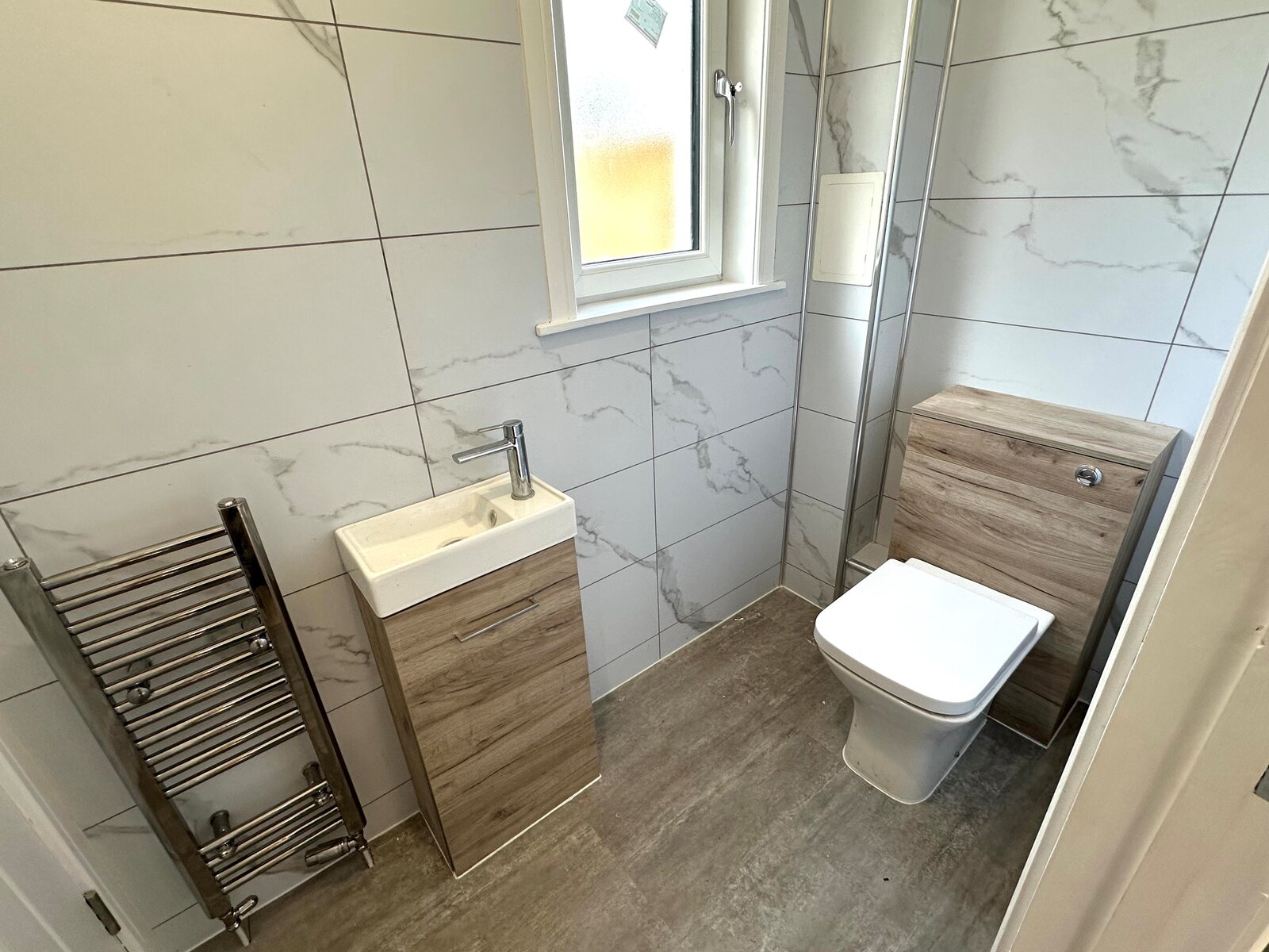 Completed cloakroom with marble-effect tiles and compact fittings